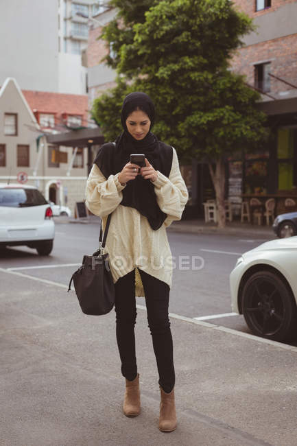 Красива міська хіджаб жінка використовує мобільний телефон на тротуарі — стокове фото