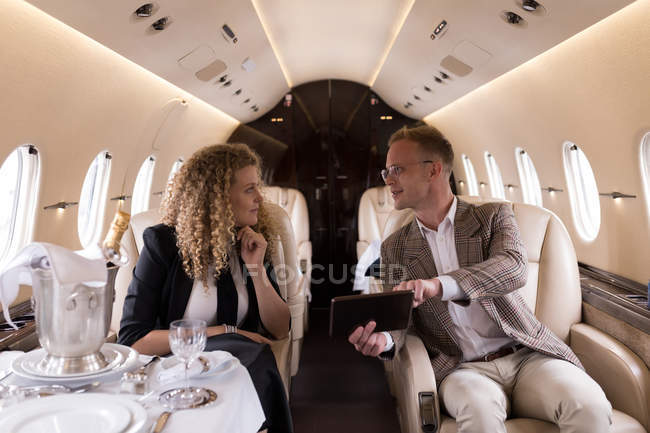 Businesspeople discussing over digital tablet in private jet — Stock Photo