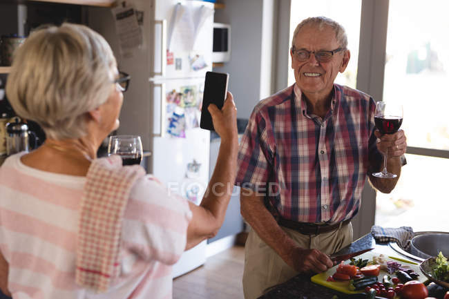 Старша жінка натискає фотографію чоловіка на кухні вдома — стокове фото