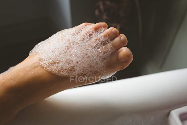 Primo piano della gamba delle donne ricoperta di schiuma in bagno — Foto stock