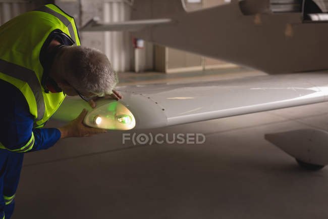 Ingenieur untersucht Licht von Flugzeugen im Hangar der Raumfahrt — Stockfoto