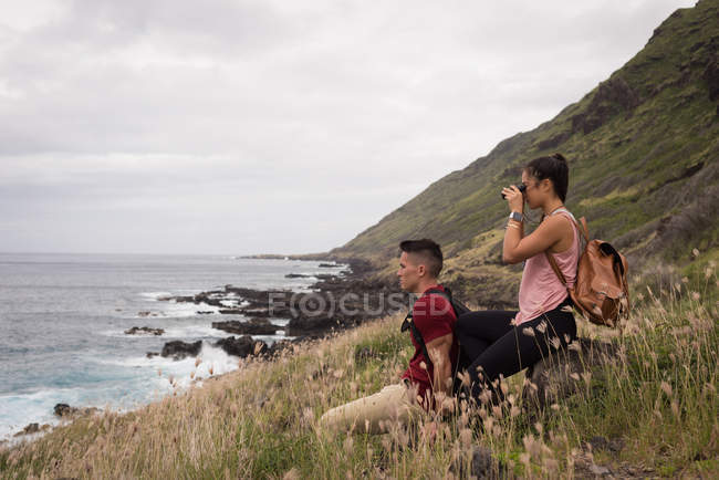 Jeune couple regardant à travers les jumelles à la campagne — Photo de stock