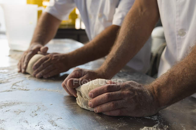 Чоловік пекар готує тісто зі своїм колегою в хлібопекарні — стокове фото