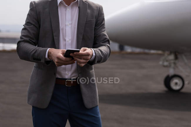 Mid section of businessman using mobile phone at terminal — Stock Photo