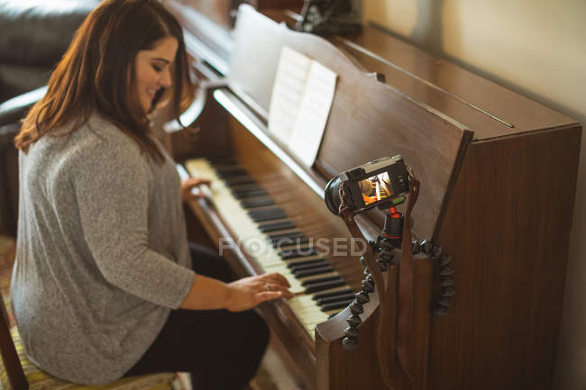 Красивая женщина-блогер играет дома на пианино — стоковое фото