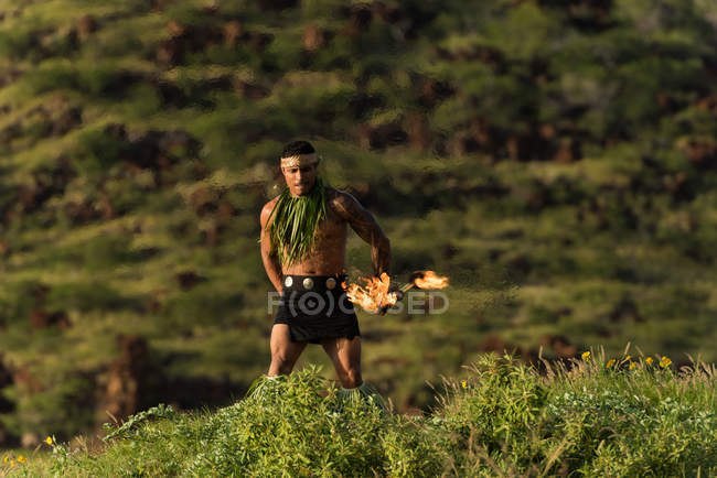 Male fire dancer performing with fire levi stick near beach — Stock Photo