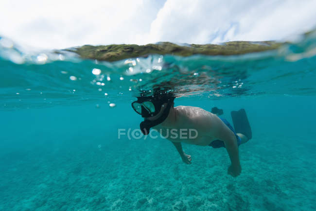 Homme faisant de la plongée sous-marine en mer turquoise par côte — Photo de stock