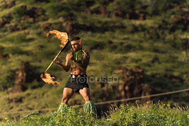 Male fire dancer performing with fire levi stick near beach — Stock Photo