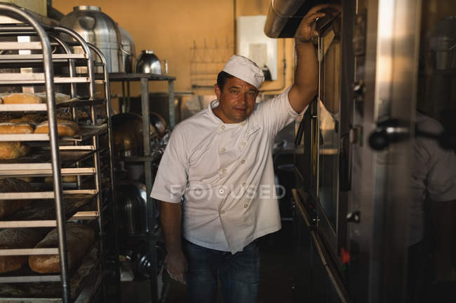 Retrato del panadero de pie en la panadería - foto de stock