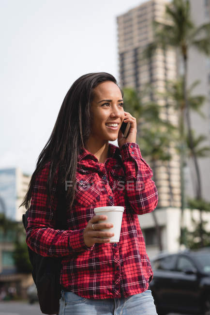 Smiling woman talking on mobile phone on city street — Stock Photo