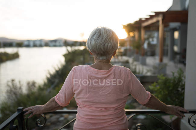 Вид сзади на пожилую женщину, стоящую на балконе — стоковое фото