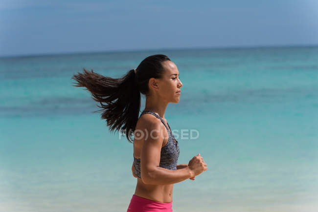 Женщина бегает по пляжу в солнечный день — стоковое фото