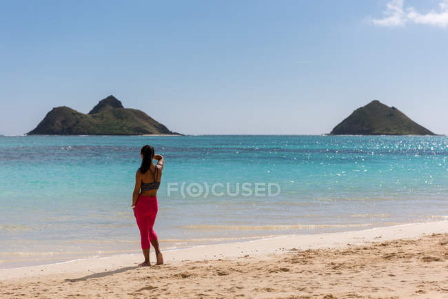 Rückansicht einer Frau, die an einem sonnigen Tag am Strand steht — Stockfoto