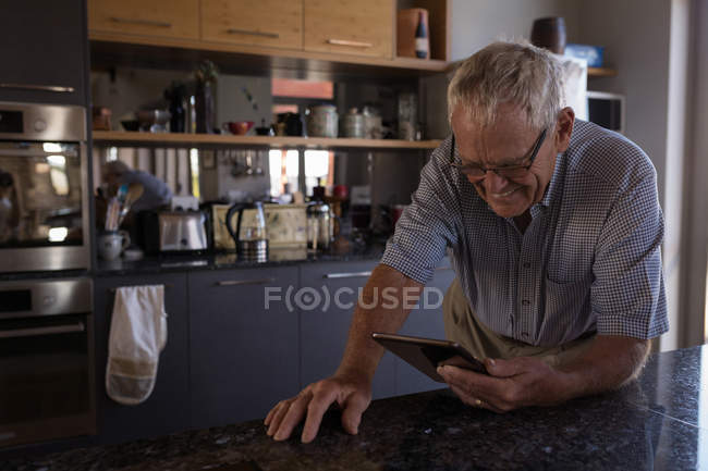 Senior man video calling on digital tablet in kitchen at home — Stock Photo