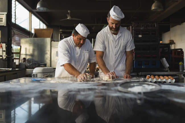 Maschio panettiere preparare pasta con il suo collega in panetteria — Foto stock