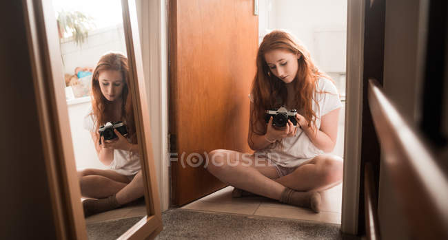 Beautiful woman holding camera at home — Stock Photo