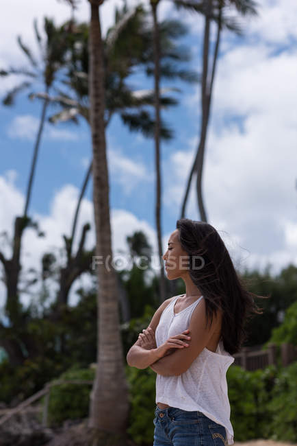 Young woman standing with arms crossed in the beach — Stock Photo