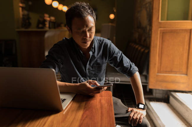 Homem de negócios concentrado usando telefone celular no café — Fotografia de Stock