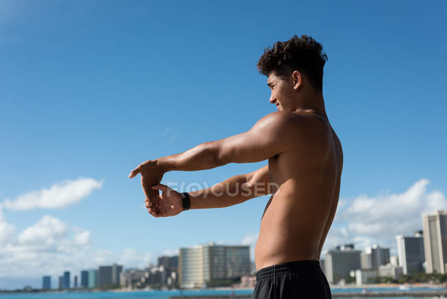 Молодой человек тренируется у моря в солнечный день — стоковое фото