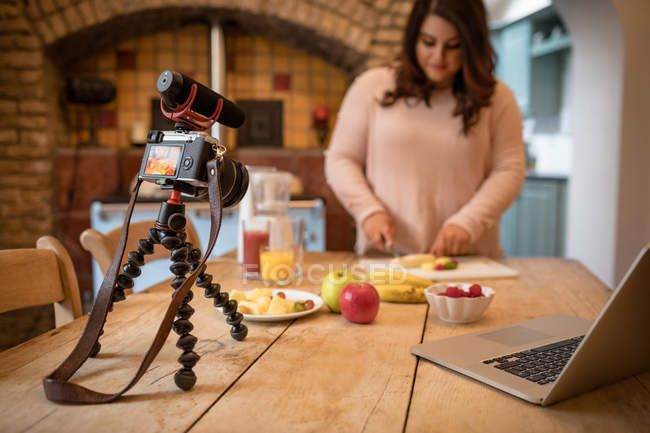 Femmina vlogger taglio frutta sul tagliere a casa — Foto stock