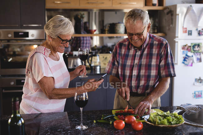 Старшая пара резки овощей на кухне на дому — стоковое фото