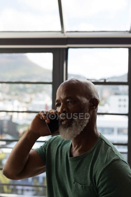 Крупный план пожилого человека, разговаривающего по мобильному телефону дома — стоковое фото