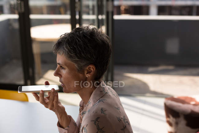 Mature businesswoman talking on mobile phone in the office — Stock Photo