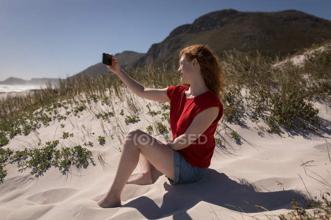 Красивая женщина делает селфи на песке на пляже — стоковое фото