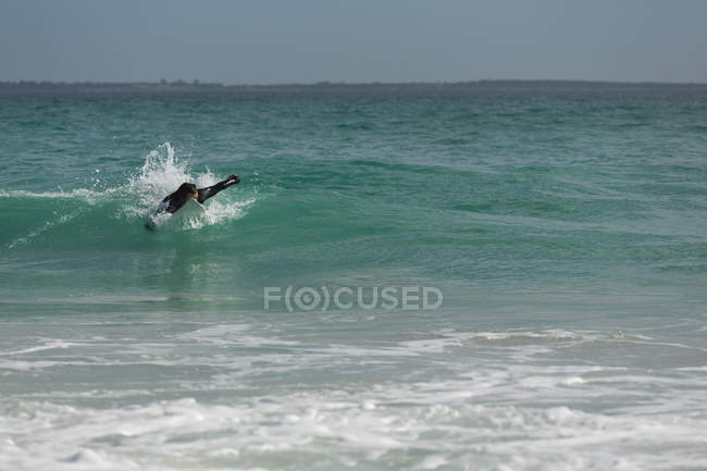 Surferin surft an einem sonnigen Tag am Strand — Stockfoto