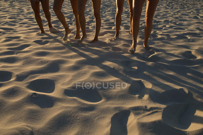 Sección baja de jugadoras de voleibol corriendo en la playa - foto de stock