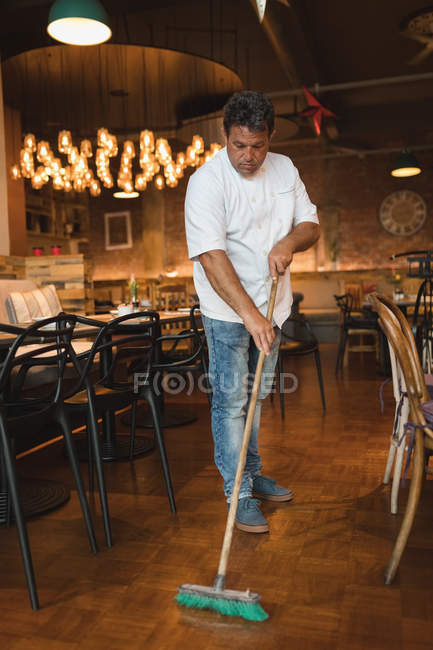 Male baker cleaning floor with floor mop in cafe — Stock Photo