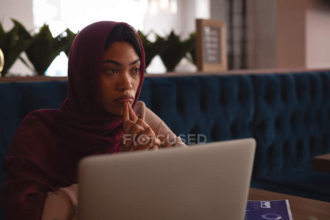 Pensativa mujer de negocios en hijab relajarse en la cafetería - foto de stock