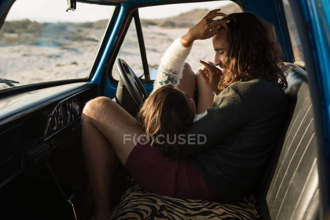Casal relaxante em um caminhão de coleta na praia em um dia ensolarado — Fotografia de Stock