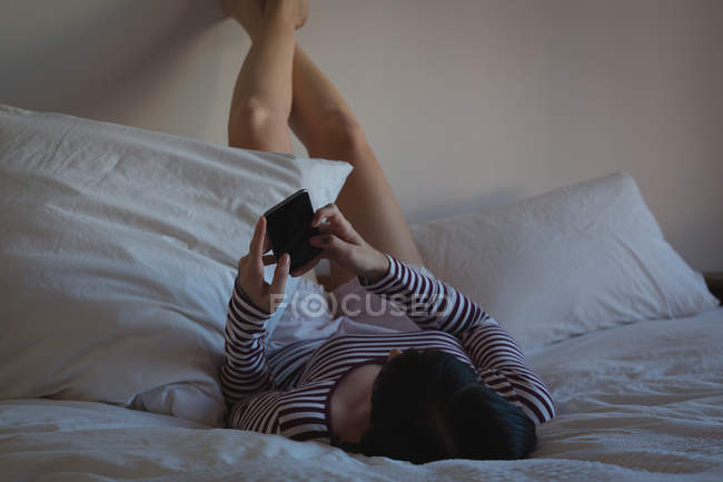 Женщина с мобильного телефона в спальне дома — стоковое фото
