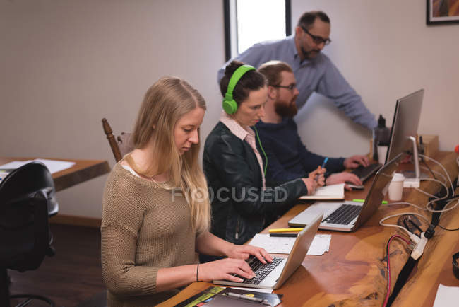 Business colleagues working on laptop at desk in office — Stock Photo