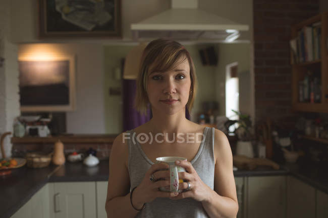 Portrait de belle femme tenant une tasse de café à la maison — Photo de stock
