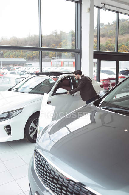 Vendedor examinando carro no showroom — Fotografia de Stock