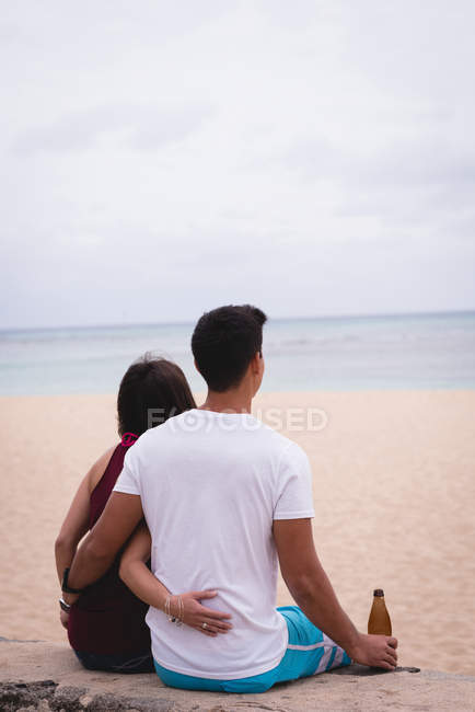 Rückansicht eines Paares, das zusammen am Strand sitzt — Stockfoto
