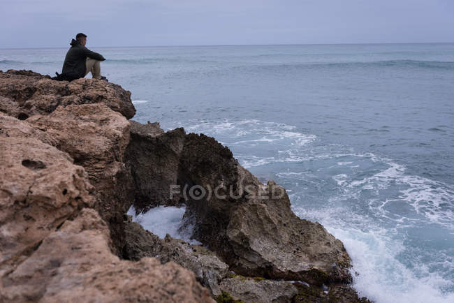 Frau entspannt sich an einem sonnigen Tag auf einem Felsen am Strand — Stockfoto