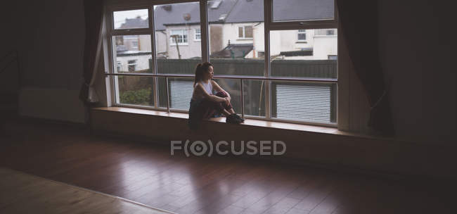 Bailarina femenina pensativa mirando por la ventana en el estudio de danza - foto de stock