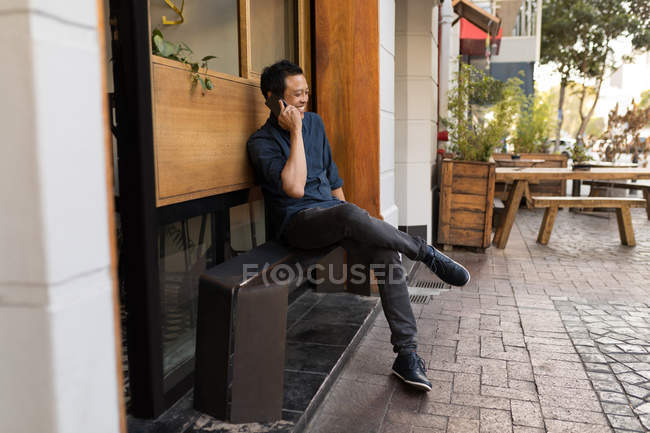 Smiling businessman talking on phone in the pavement cafe — Stock Photo