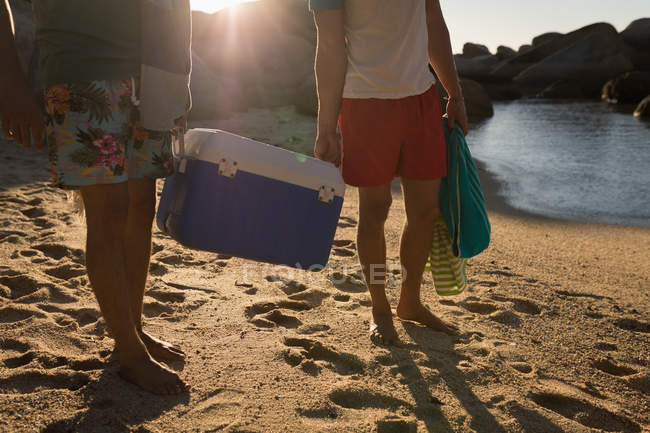 Amici maschi che trasportano esky in spiaggia in una giornata di sole — Foto stock