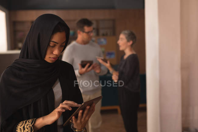 Businesswoman in hijab using digital tablet at office cafeteria — Stock Photo