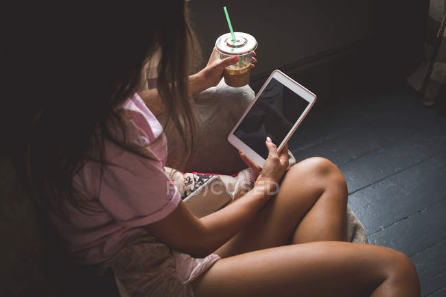Frau trinkt kalten Kaffee mit digitalem Tablet zu Hause — Stockfoto