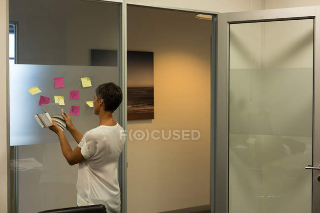 Mulher de negócios madura trabalhando sobre notas pegajosas no escritório — Fotografia de Stock