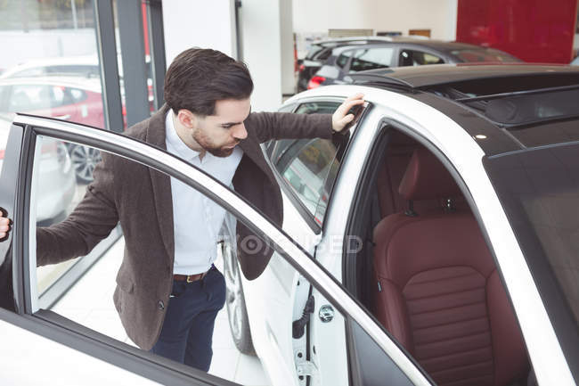 Красивый продавец осматривает машину в выставочном зале — стоковое фото