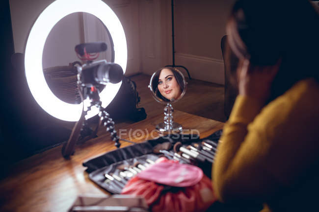 Registrador de vídeo femenino aplicando maquillaje en casa - foto de stock