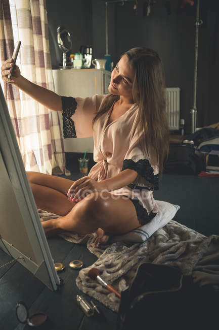 Mulher bonita tomando selfie com telefone celular em casa — Fotografia de Stock