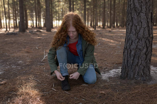 Жінка зав'язує взуття мереживом в лісі в сонячний день — стокове фото