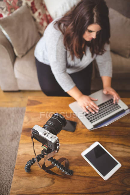 Femme vlogger assis sur le canapé tout en utilisant un ordinateur portable à la maison — Photo de stock